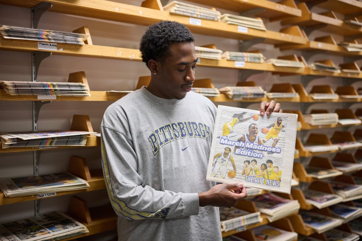 Jermaine Sykes, assistant sports editor, poses for a photo with a copy of ϲʿ March Madness Edition.